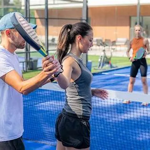 Entrenador enseñando técnica de pádel a una alumna